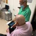Scott Gartner, O.D., optometrist, shows Miami Lighthouse senior patient how to use electronic handheld magnifier.